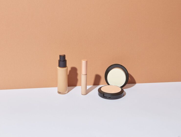 Three nude-toned cosmetic products on a neutral background