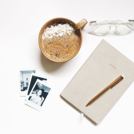 A ceramic cup beside an open notebook and pen