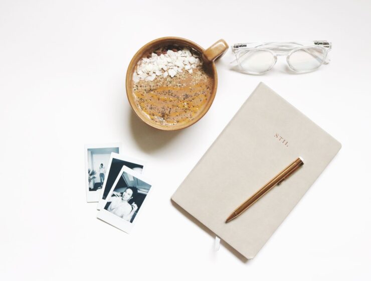 A ceramic cup beside an open notebook and pen