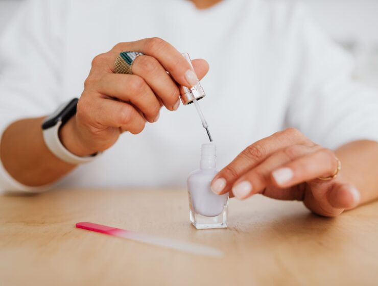 A hand holding a bottle of white nail polish